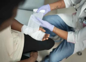 Profissional de saúde enfaixando a mão ferida de um paciente, ilustrando tratamento de feridas com solução PHMB
