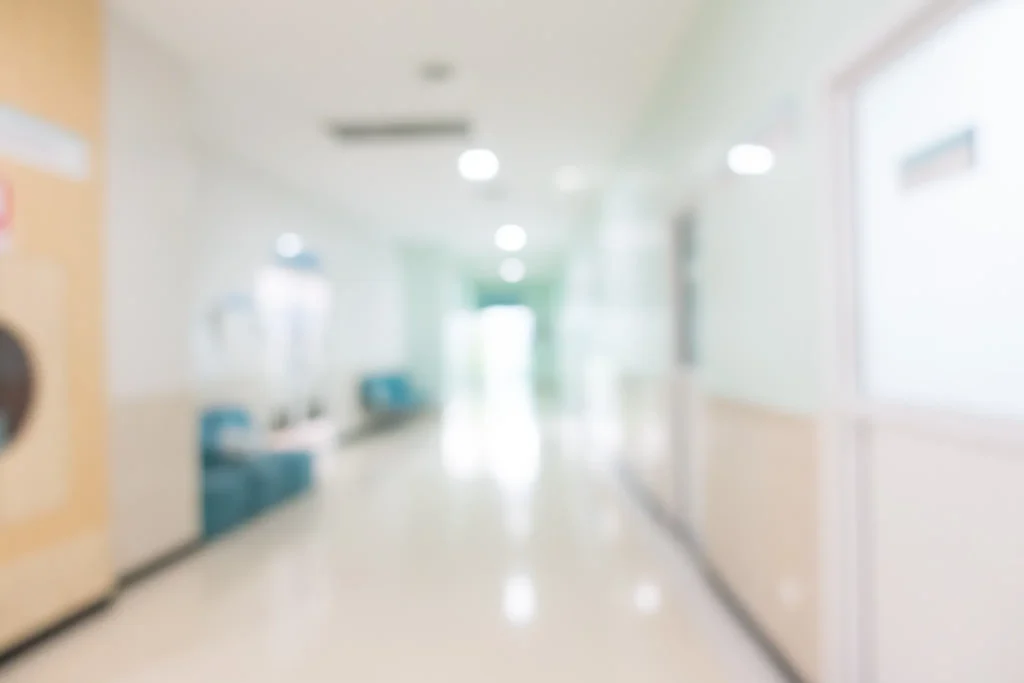 Corredor de hospital desfocado representando ambiente clínico voltado à acreditação laboratorial